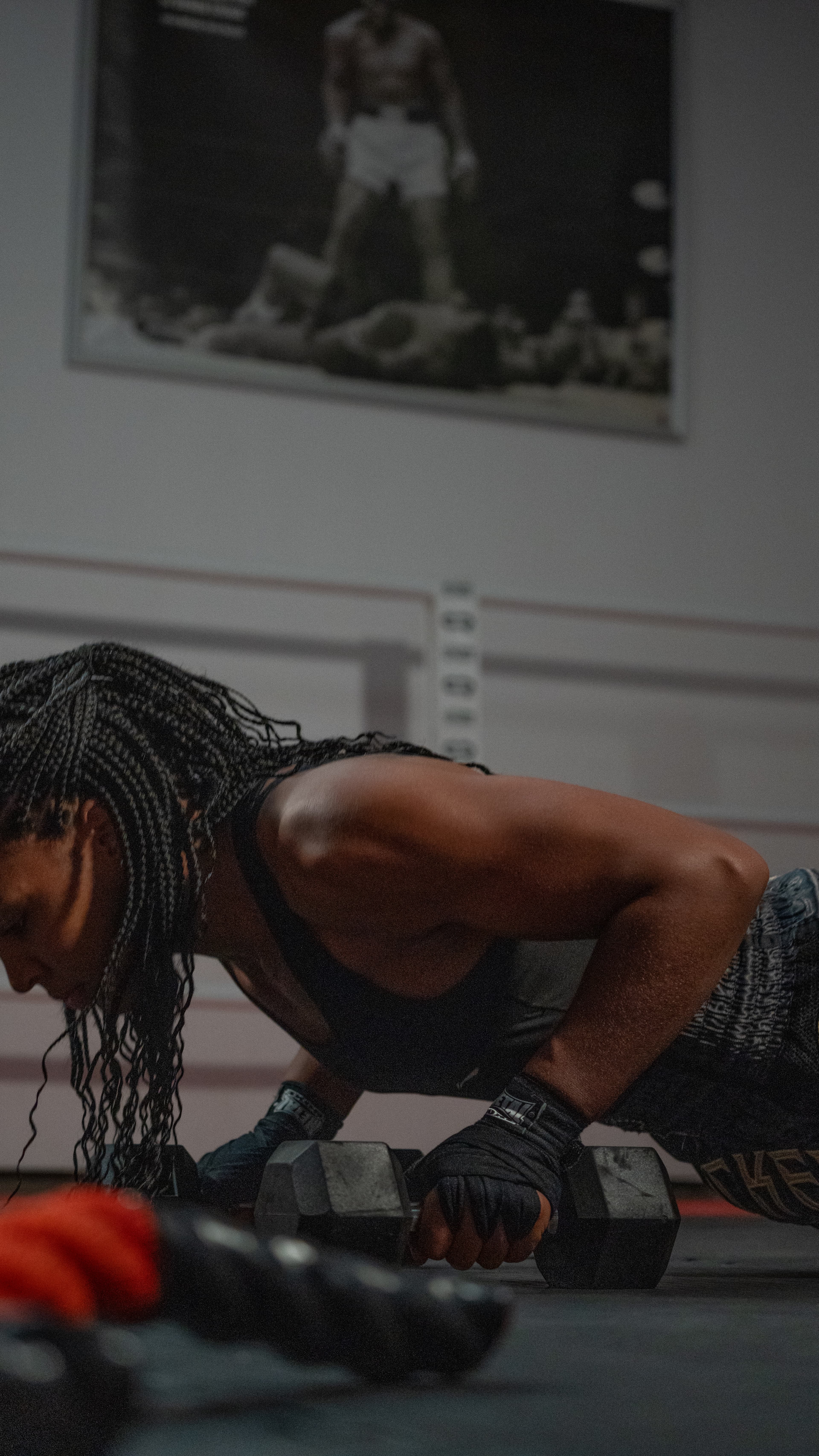 Athlète faisant des pompes mains sur haltères dans une salle de sport, cadrage rapproché au sol