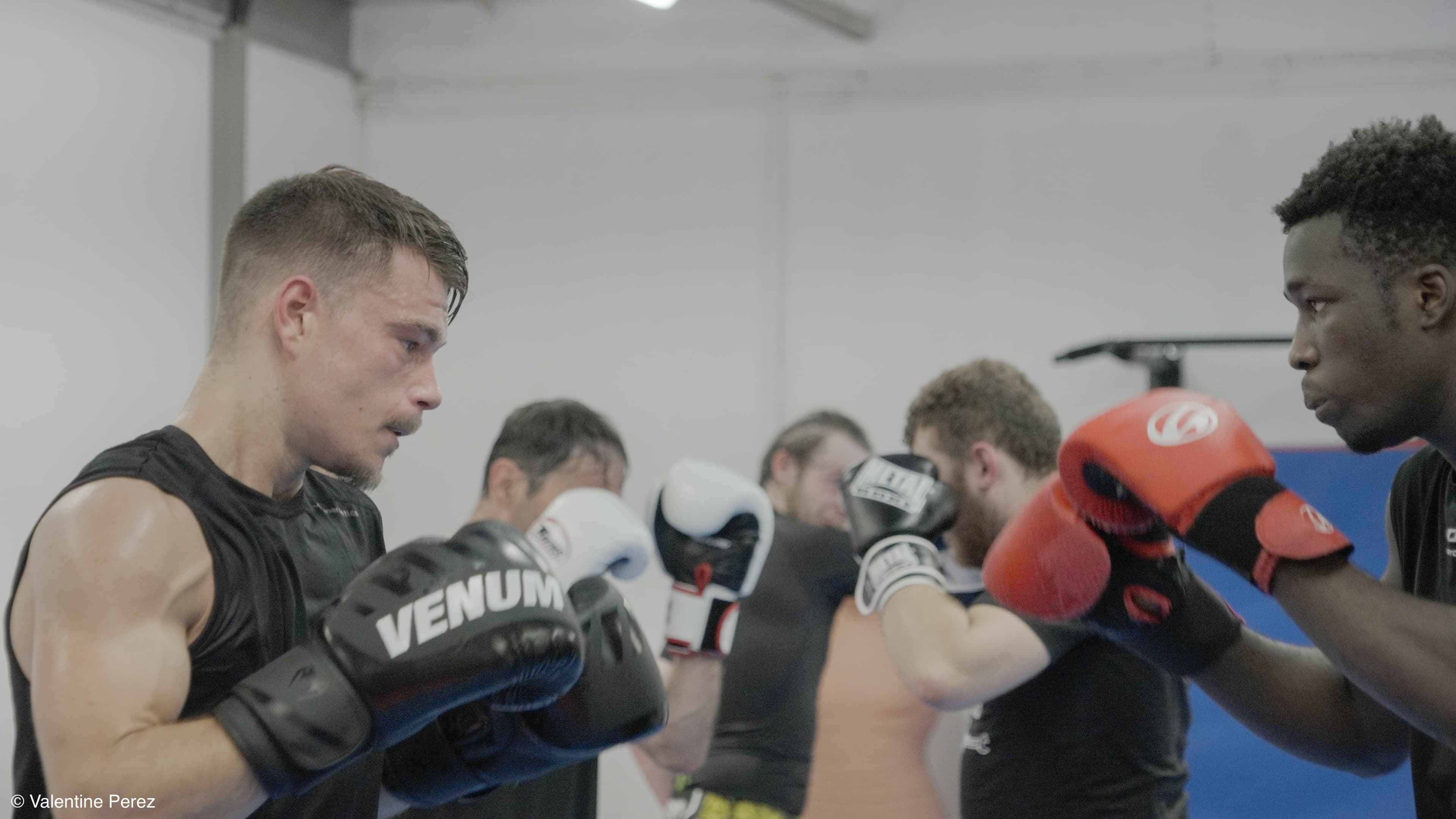 Deux personnes en plein échange de coups lors d’un entraînement de kick-boxing, avec des gants et protections